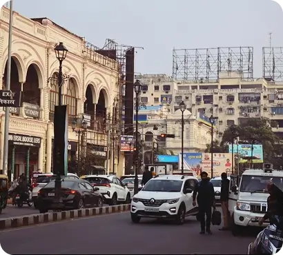 Busy street scene in Lucknow with buildings, cars, and people. Keywords: Lucknow city, street view, urban landscape.