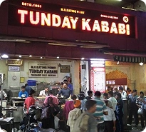 Crowded Tunday Kababi restaurant in Lucknow with a bright red sign. Keywords: Tunday Kababi, Lucknow food, famous restaurant.