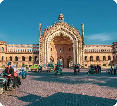 Historic architectural archway building in Lucknow with people and rickshaws outside. Keywords: Lucknow architecture, historical landmark, tourism.